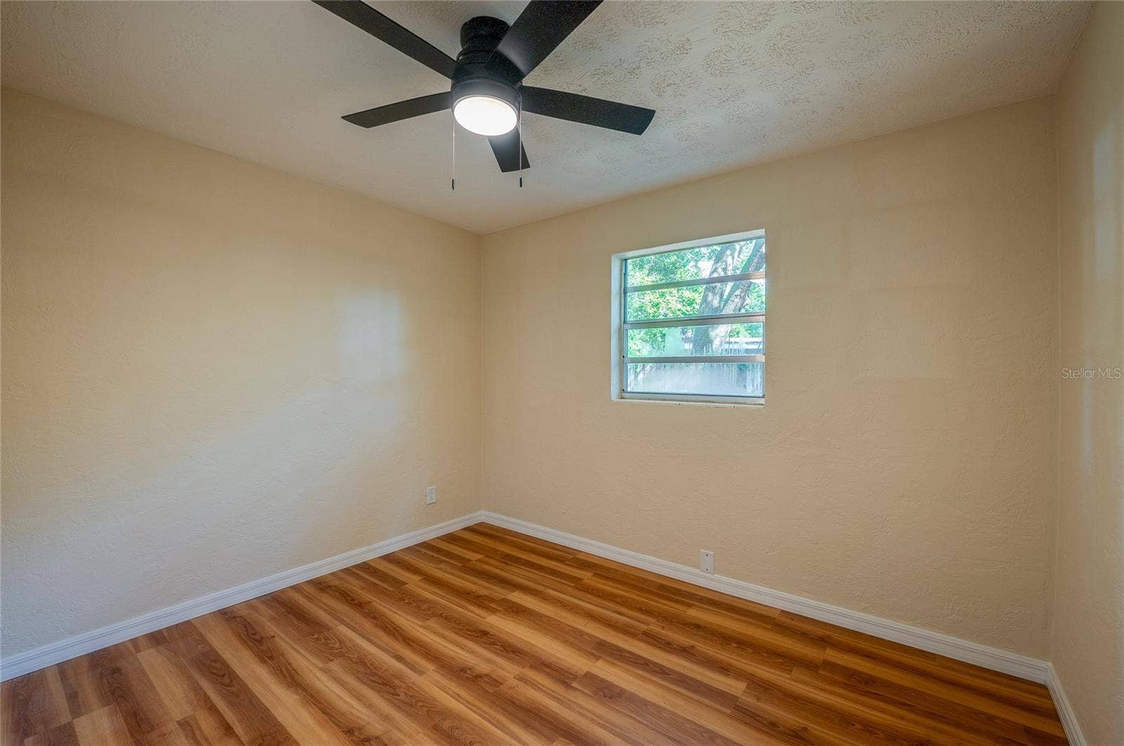 1220 LEON LANE, Daytona Beach, FL 32117 Bright bedroom featuring a ceiling fan, neutral finishes, and a window that brings in natural light, offering a comfortable and versatile space.