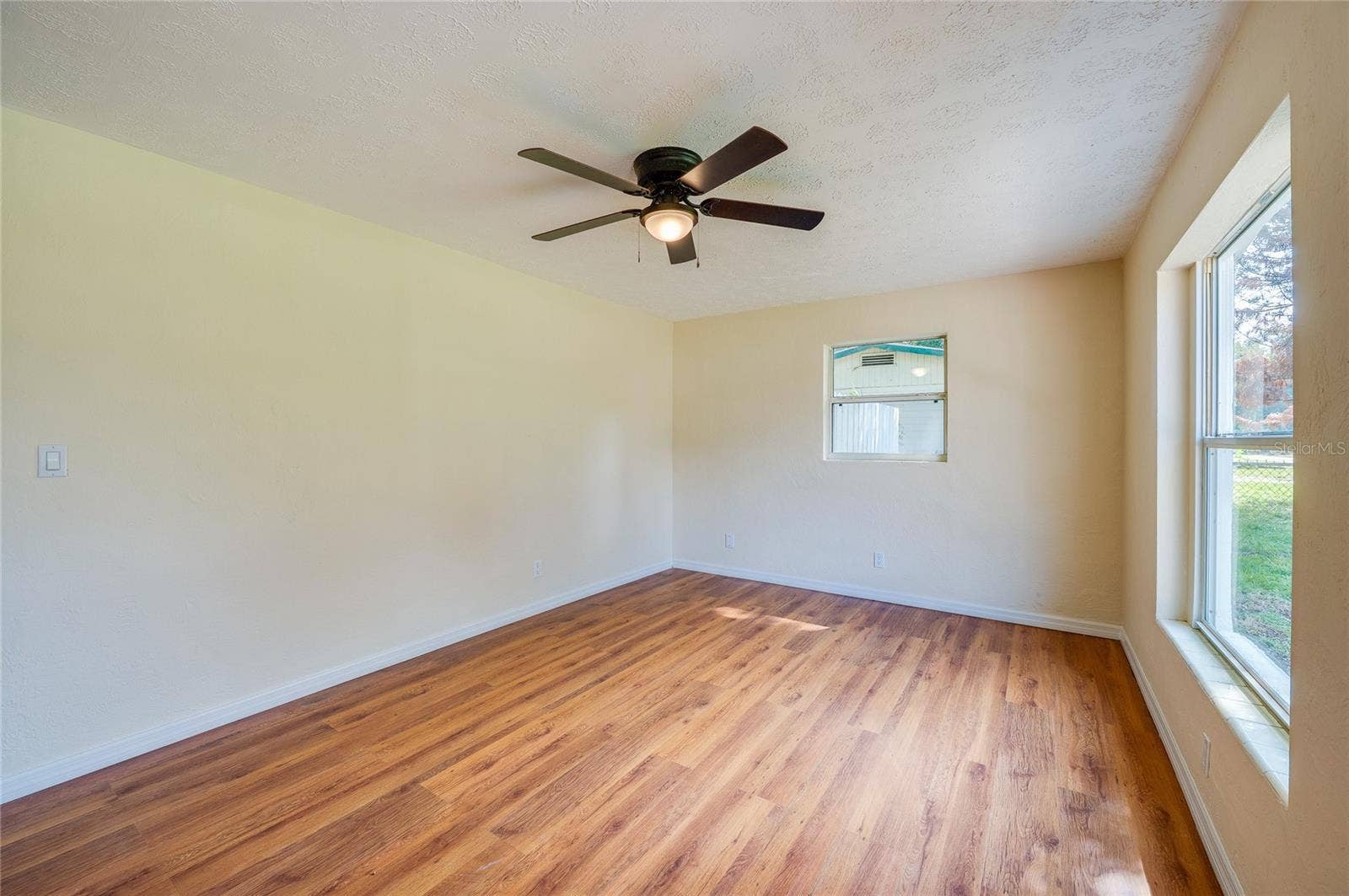 1220 LEON LANE, Daytona Beach, FL 32117 Bright and spacious living room featuring large windows, neutral finishes, and ceiling fan for year-round comfort.