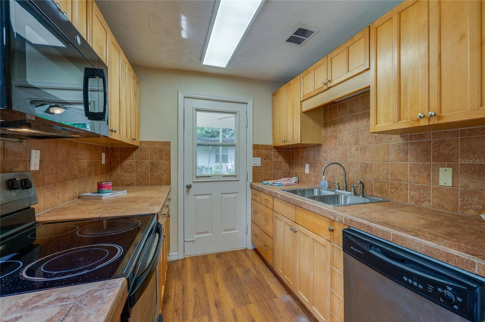 1220 LEON LANE, Daytona Beach, FL 32117 Functional kitchen with double-basin sink, abundant storage, expansive countertops, and an efficient workspace.