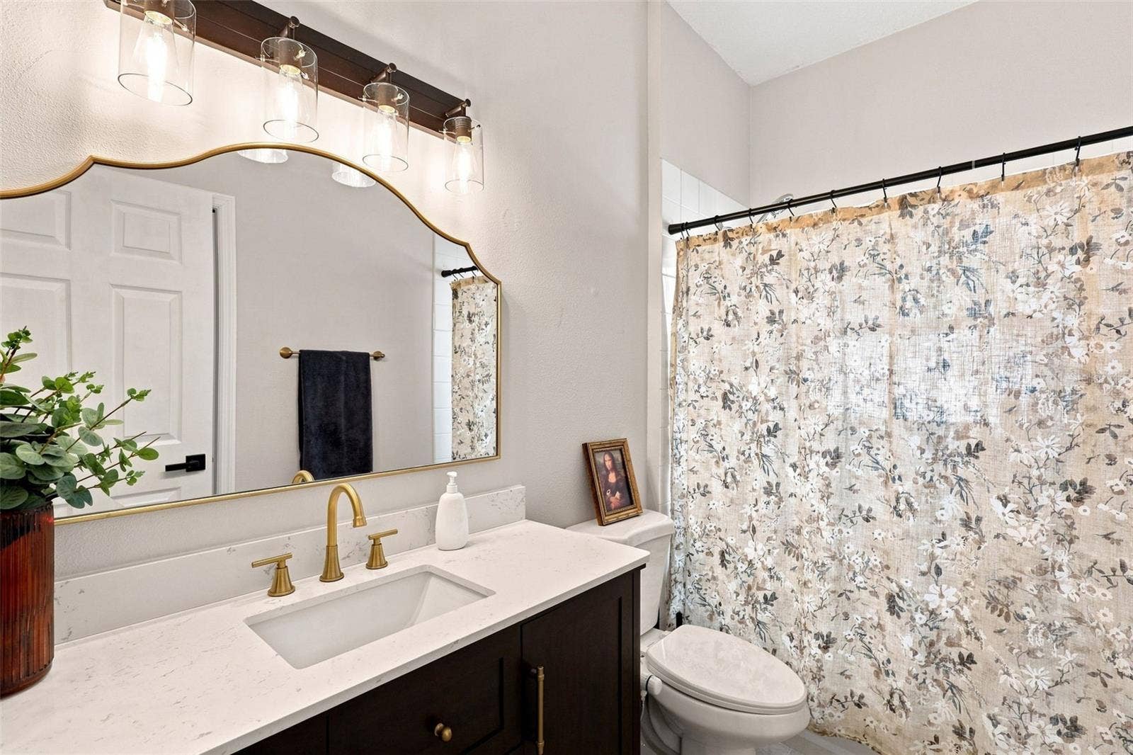 Guest bath with quartz countertops and tub-shower combo.