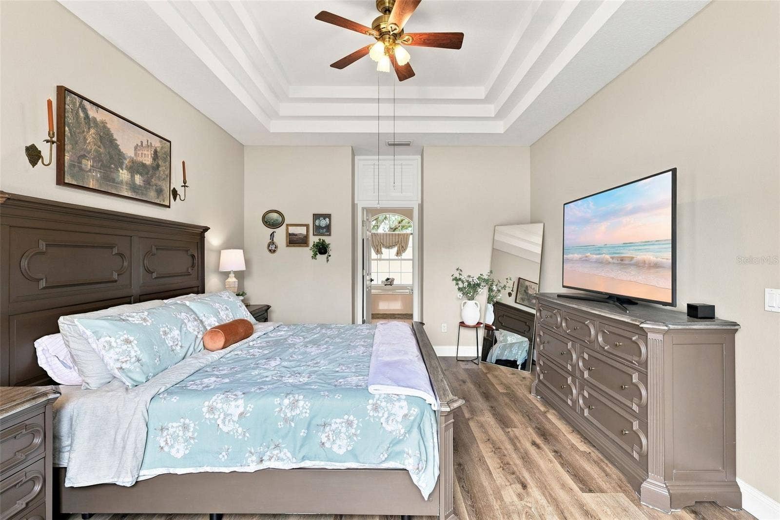 Primary bedroom with gorgeous tray ceiling and ceiling fan.