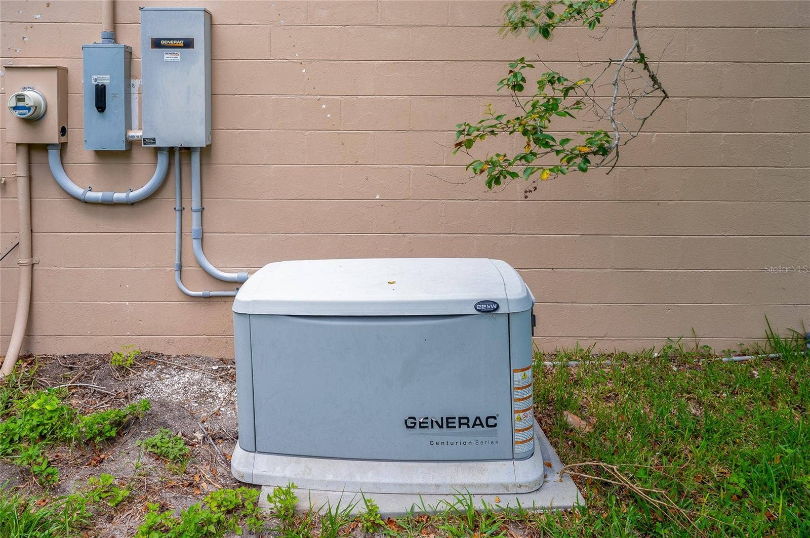 156 SPRINGWOOD DRIVE, Daytona Beach, FL 32119 Exterior utility section featuring an outdoor whole-home Generac standby generator unit set on a concrete pad. Wall-mounted electrical panels and conduits are installed neatly along the painted block wall.