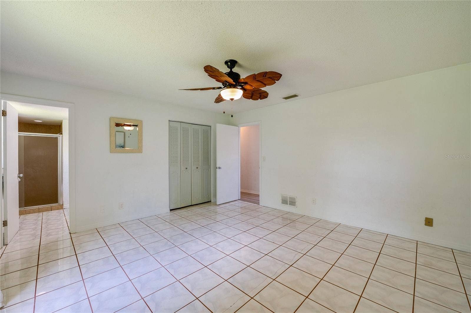 156 SPRINGWOOD DRIVE, Daytona Beach, FL 32119 Expansive room featuring easy-to-clean tile floors, a decorative ceiling fan, and closet doors. The open layout provides smooth access to an attached en-suite bathroom.