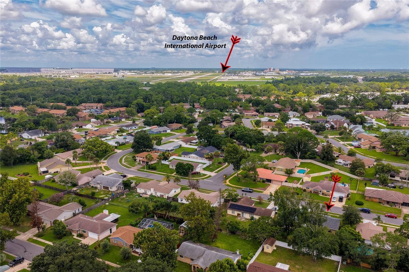 156 SPRINGWOOD DRIVE, Daytona Beach, FL 32119 Elevated neighborhood overview highlighting the home's location relative to the Daytona Beach International Airport. The vibrant community features winding residential roads, mature greenery, and spacious yards.