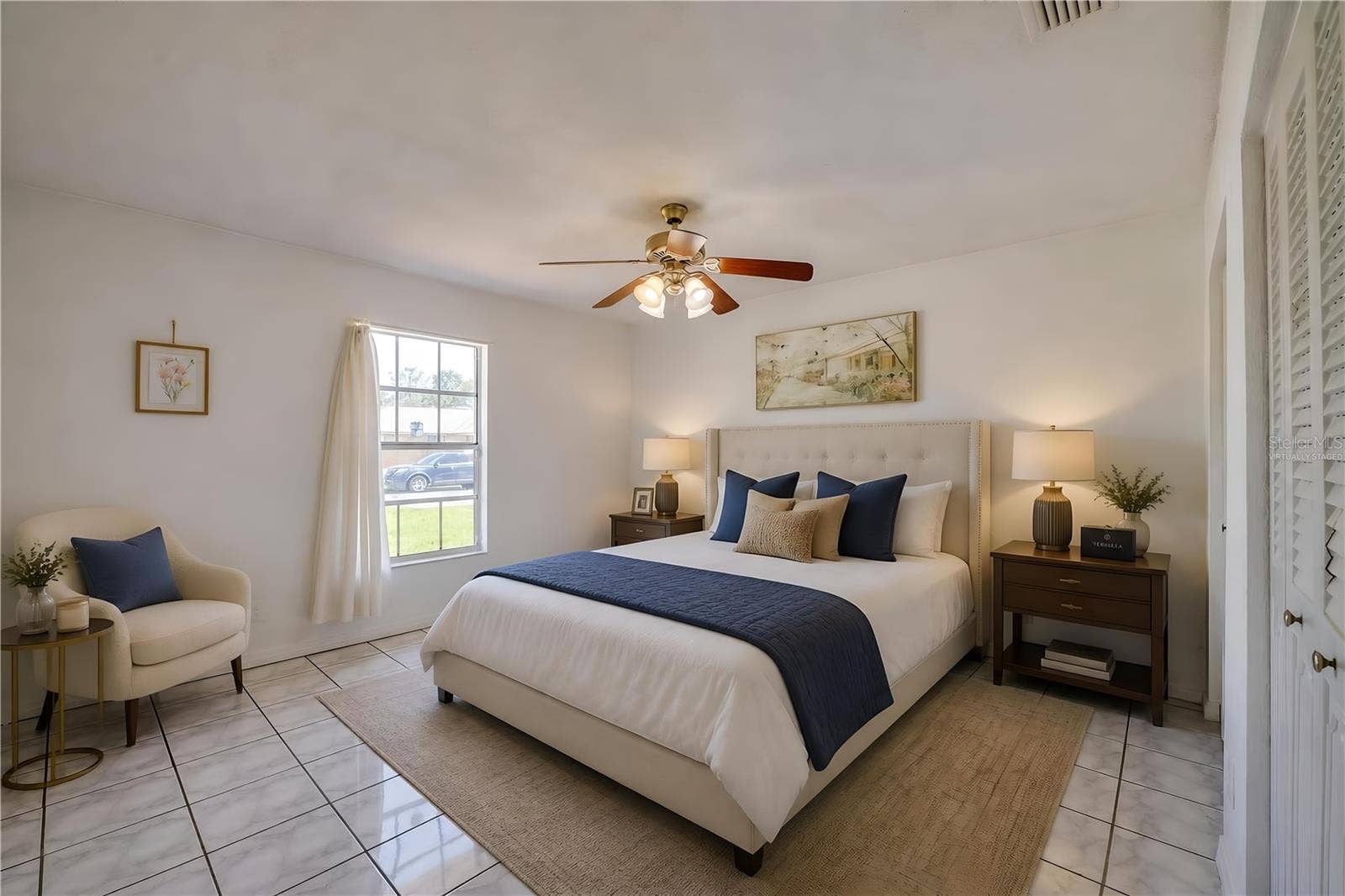156 SPRINGWOOD DRIVE, Daytona Beach, FL 32119 Virtually Staged. Spacious interior room featuring light-toned square tile flooring, neutral walls, and a wooden ceiling fan. A bright window provides natural light and views of the surrounding neighborhood.