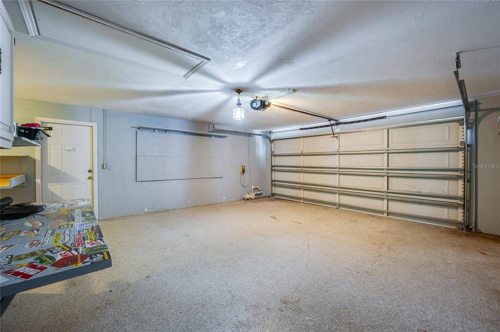 156 SPRINGWOOD DRIVE, Daytona Beach, FL 32119 Spacious two-car garage featuring finished walls, pegboard wall organization, and overhead lighting. The durable floor finish and automatic garage door opener make it ideal for storage or workshop needs.
