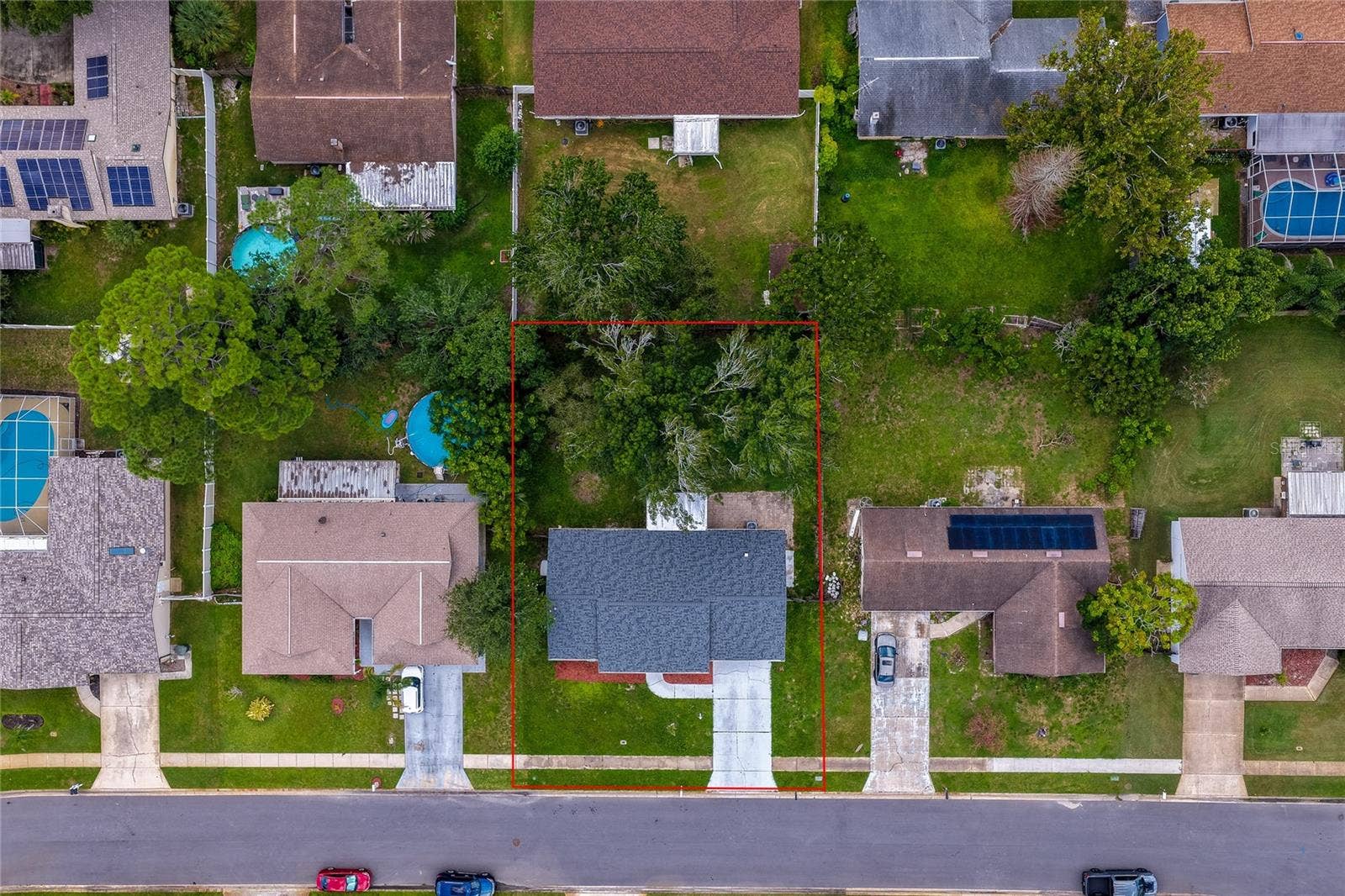 156 SPRINGWOOD DRIVE, Daytona Beach, FL 32119 Direct overhead aerial view outlining the home's property boundaries, roofline, driveway, and tree-shaded backyard layout. The surrounding neighborhood view showcases adjacent single-family properties and street layouts.