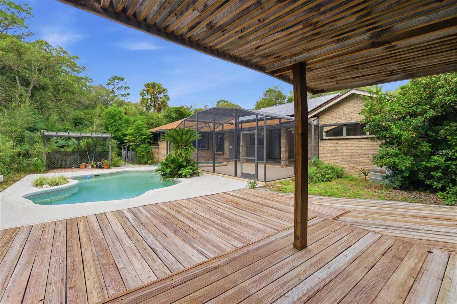 Back yard from covered deck to pool and BBQ area.