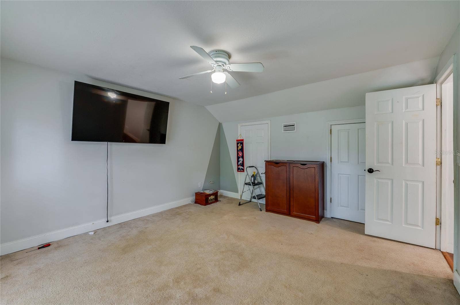 Generous room offering plush carpet flooring, sloped ceiling architecture, and a central ceiling fan.