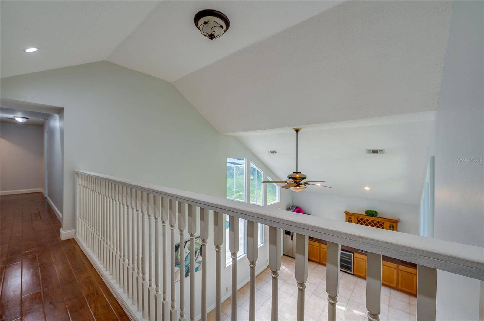 Upper-level hallway overlook featuring white balusters and a clear view down into the vaulted lower living space.