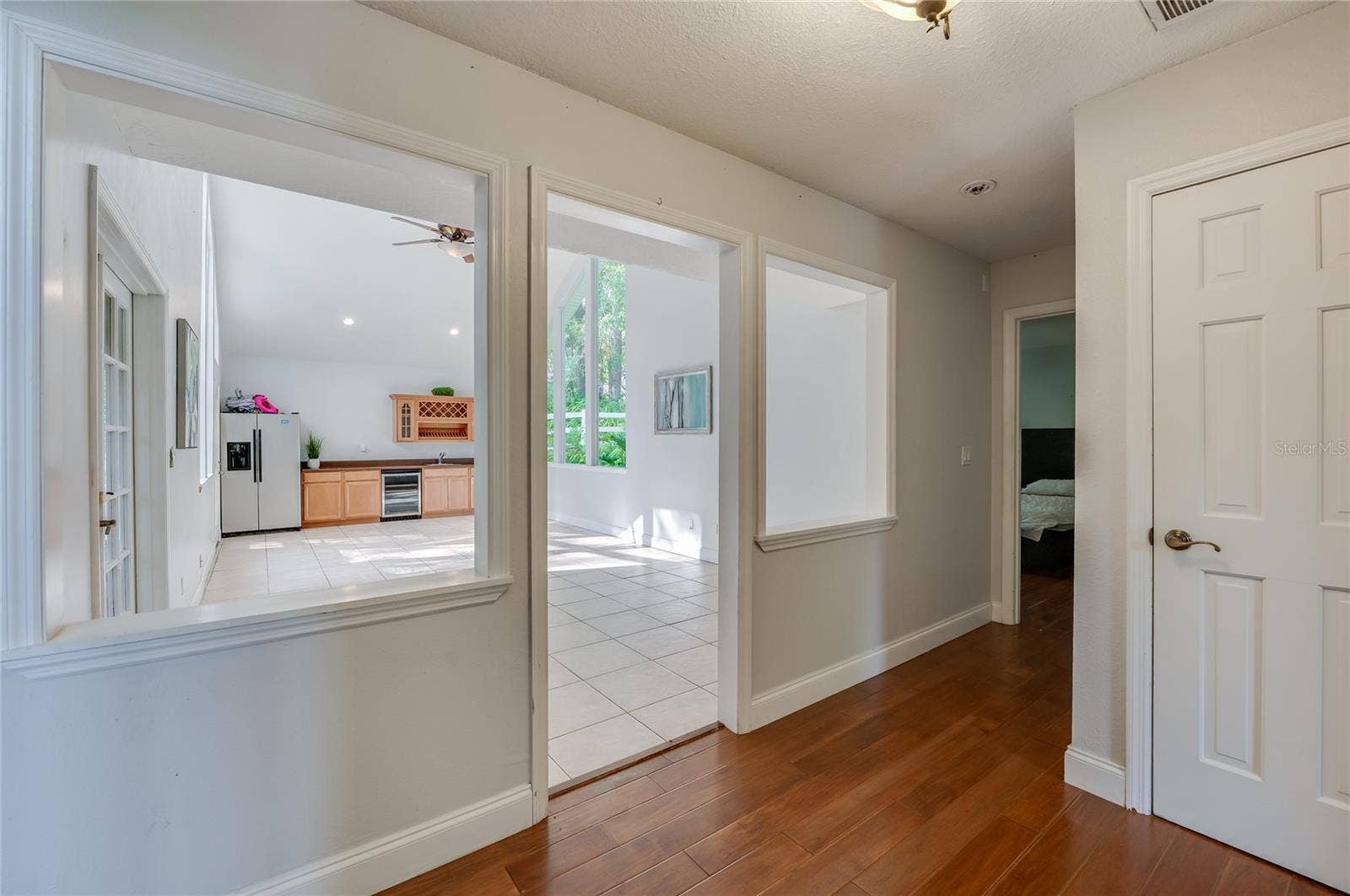 Entryway showcase featuring rich laminate flooring that opens into a bright, tiled interior flex space.