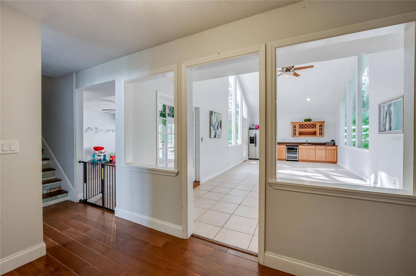 Hallway perspective highlighting warm laminate floors, architectural interior cutouts, and seamless transitions into light-filled open rooms.