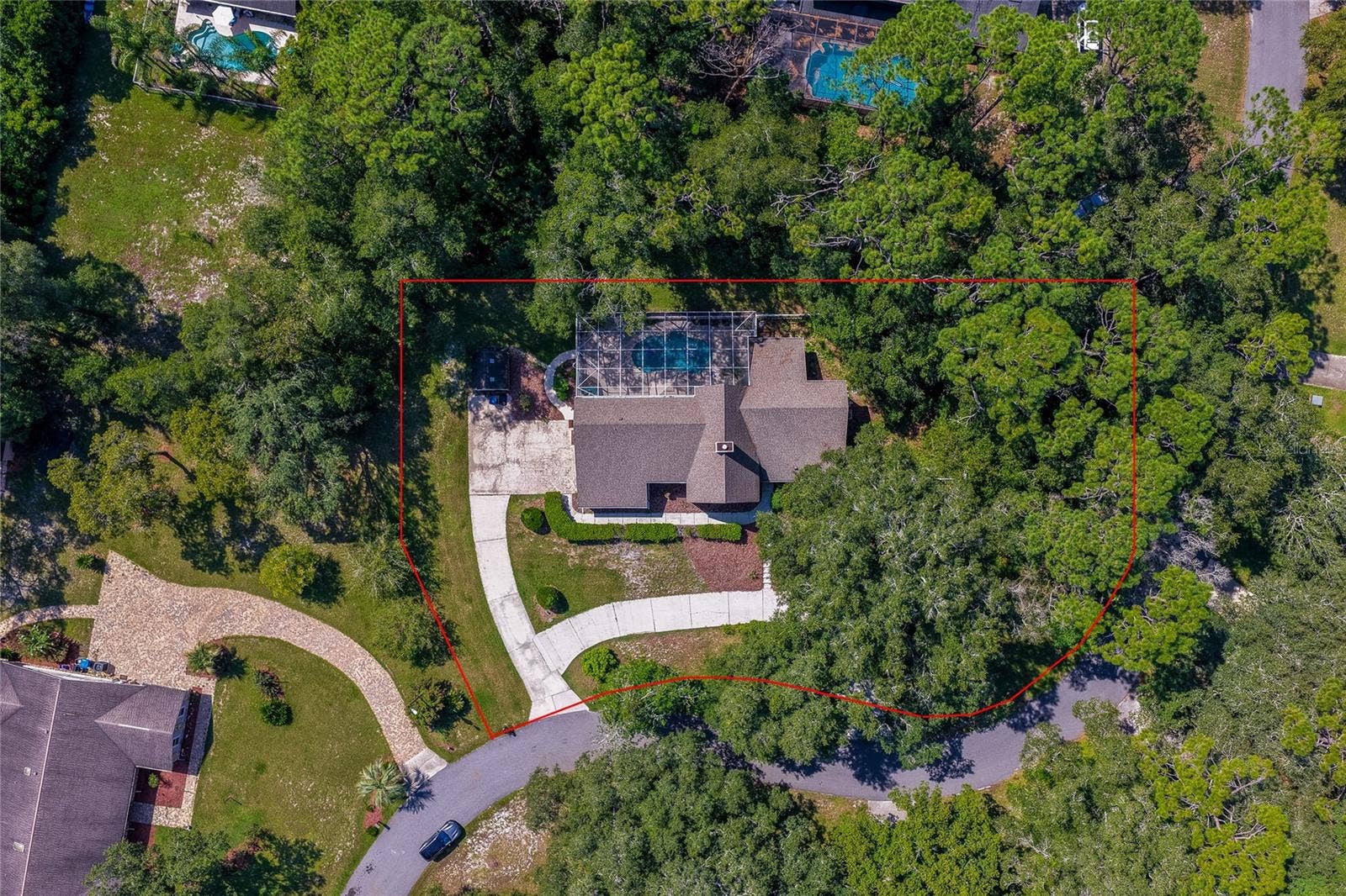 Direct overhead aerial view outlining the home's generous lot boundary surrounded by dense tree cover, a curved driveway, and a private pool enclosure.