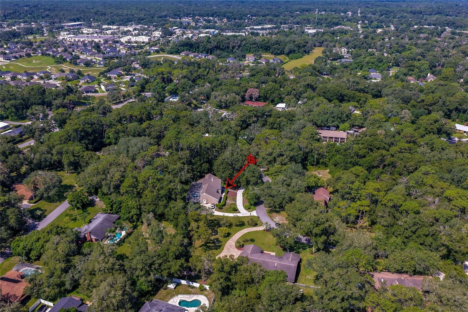 Wide aerial panorama pointing out the home nestled in a quiet, heavily wooded community setting.