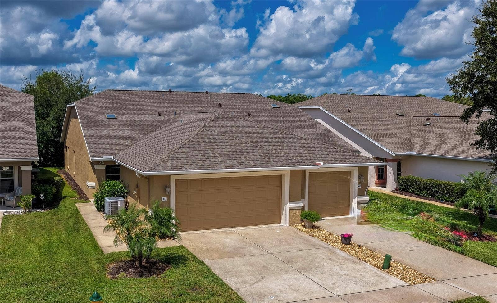 Charming home showcasing clean stucco finishes, attached garage , and a spacious concrete driveway. Simple, low-maintenance landscaping and lush green lawns complete the inviting curb appeal.