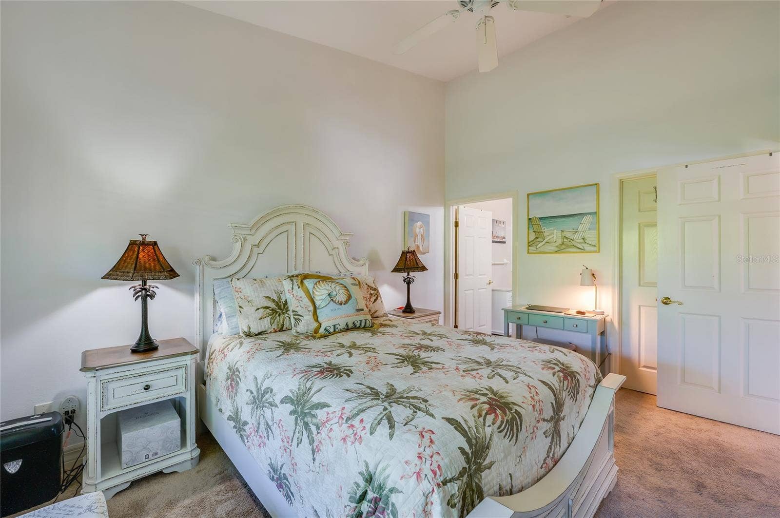 Well-proportioned bedroom with high ceilings, neutral carpet, and soft wall colors. Open doorways lead directly into an en-suite bathroom and a private closet.