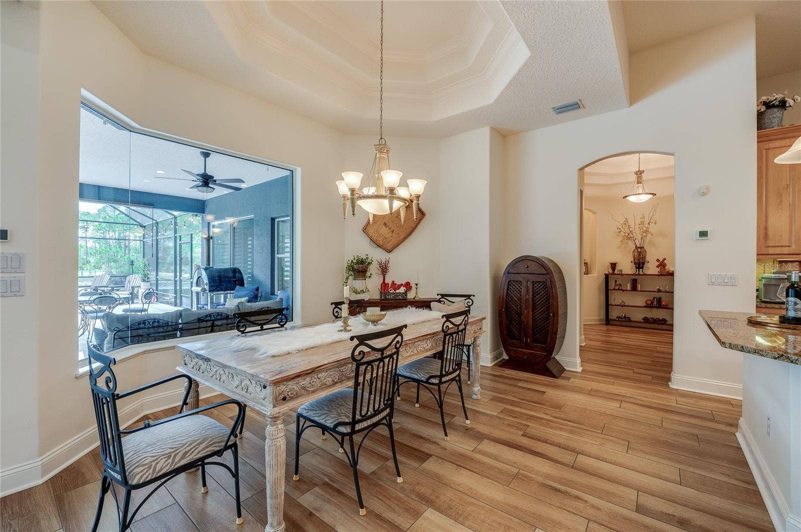 25 REMINGTON ROAD, Ormond Beach, FL 32174 Bright dining nook featuring high recessed tray ceilings, a classic chandelier, and a large seamless picture window overlooking the outdoor patio area.