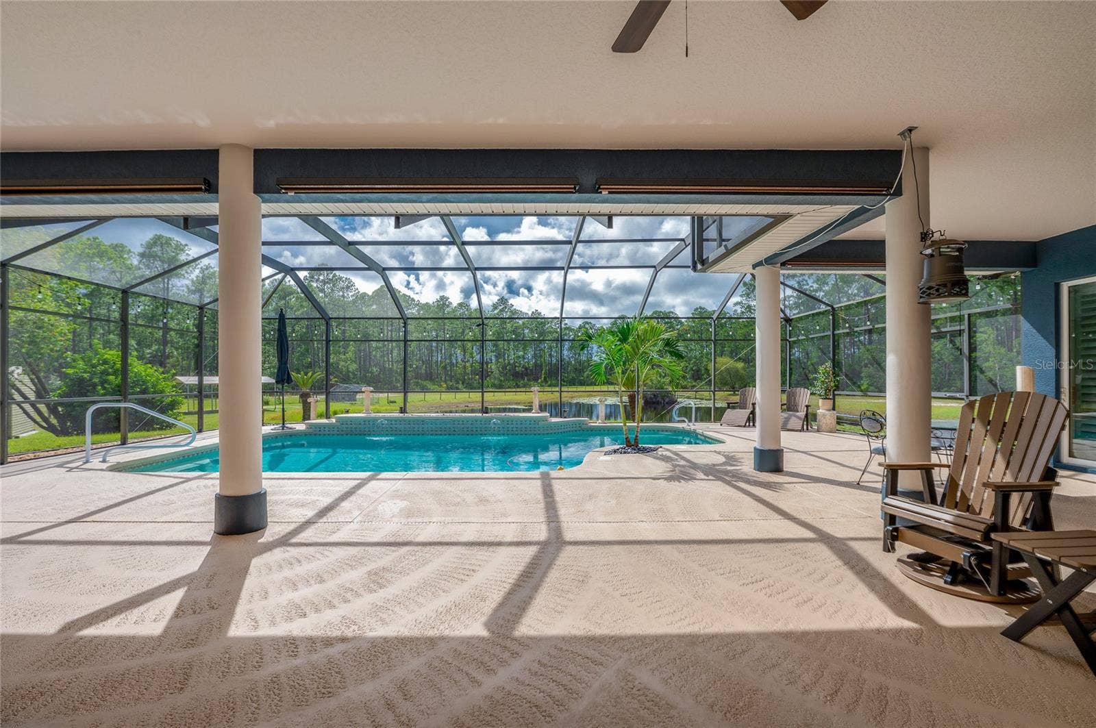 25 REMINGTON ROAD, Ormond Beach, FL 32174 Covered outdoor patio leading into a fully screened enclosure with a swimming pool and views of the surrounding natural landscape.