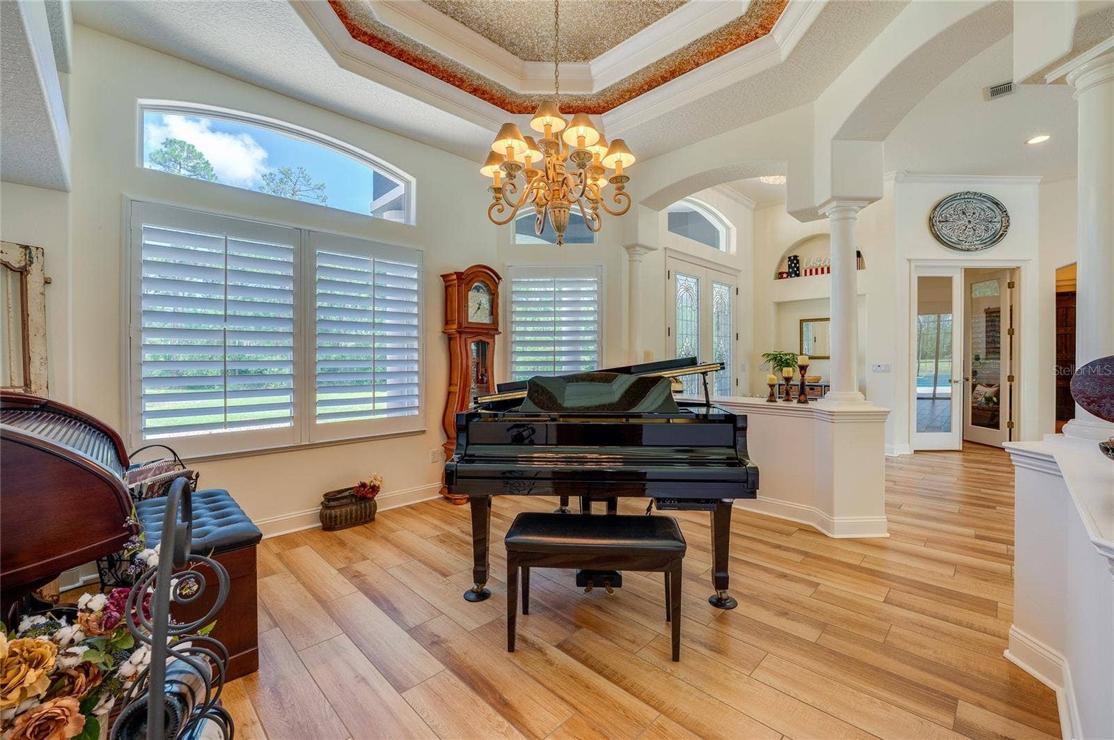 25 REMINGTON ROAD, Ormond Beach, FL 32174 Elegant formal room accented by warm tile flooring, decorative tray ceilings, an ornate chandelier, and classic shuttered windows.