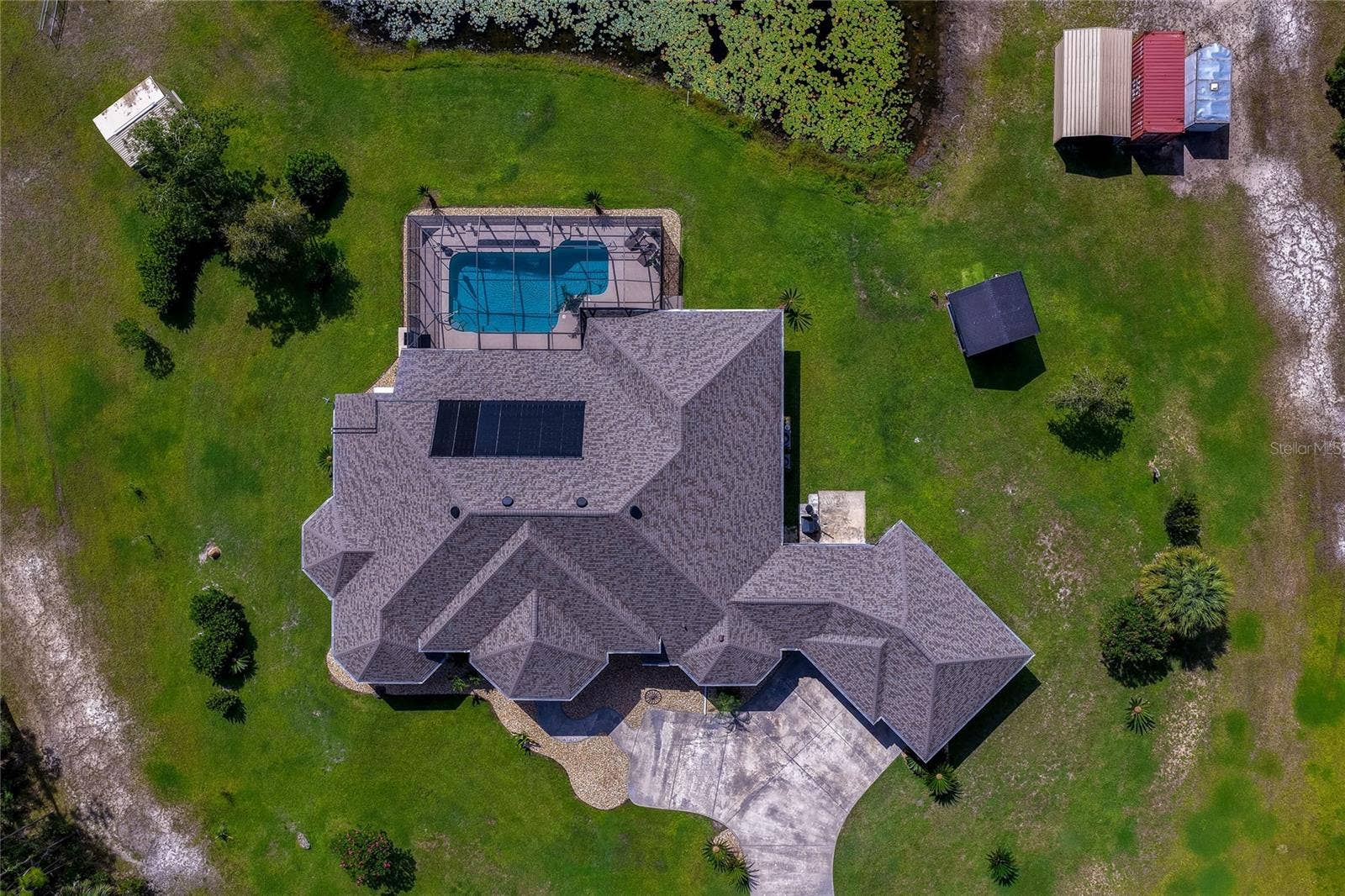 25 REMINGTON ROAD, Ormond Beach, FL 32174 Direct top-down aerial photograph detailing the architectural layout of the home's roof, solar array, screened pool deck, paved driveway, and sprawling grassy yard.
