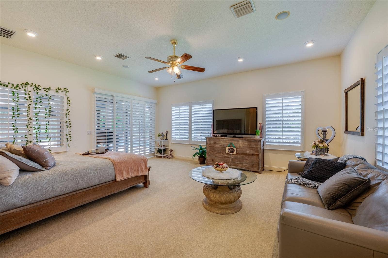 25 REMINGTON ROAD, Ormond Beach, FL 32174 Spacious room featuring plantation-shuttered windows, recessed lighting, and a neutral color palette. Natural light fills the area through a large sliding glass door.