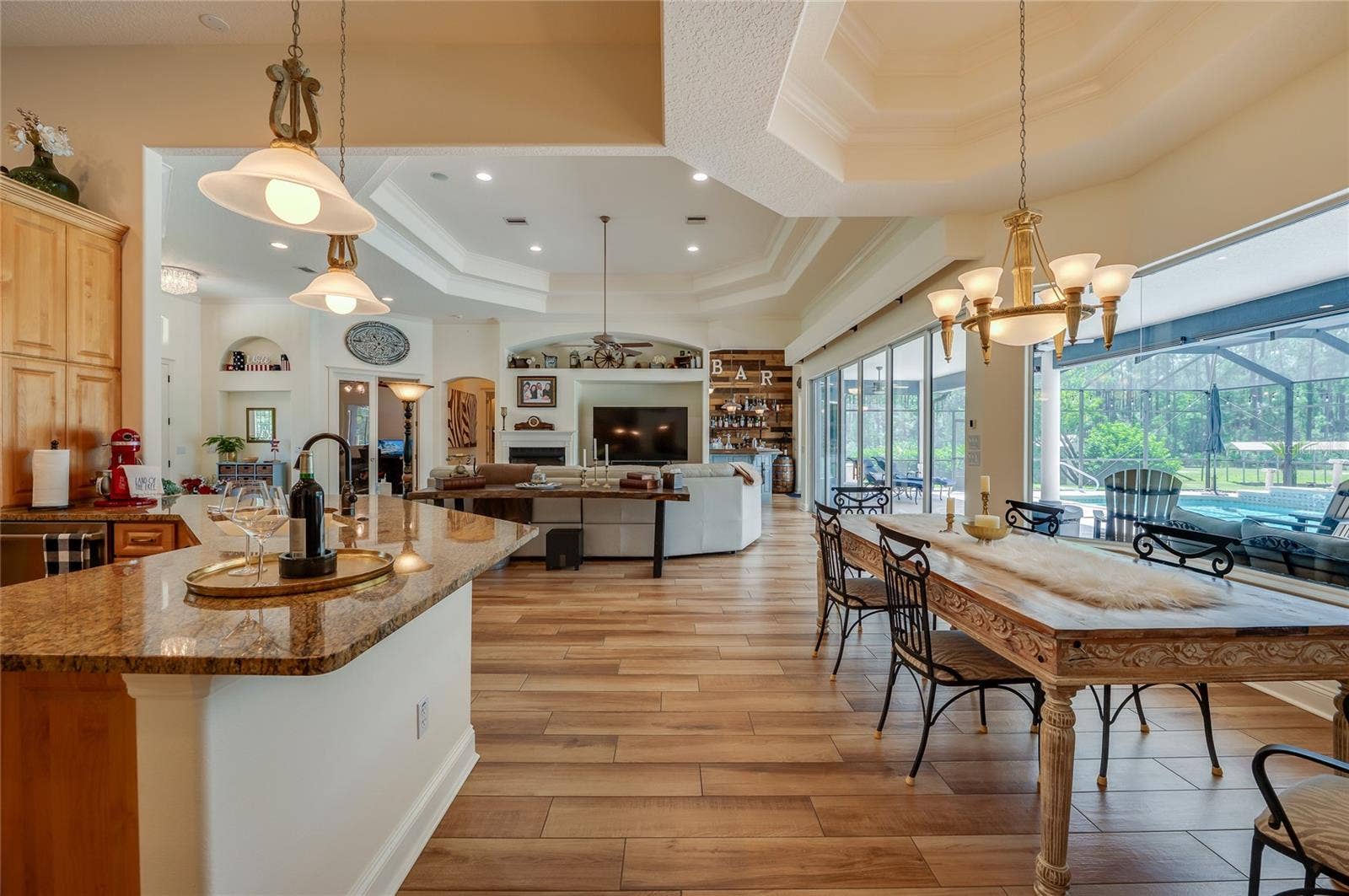 25 REMINGTON ROAD, Ormond Beach, FL 32174 Open-concept living space linking the kitchen counter and dining area to the adjacent living room with direct pool views through expansive glass doors.