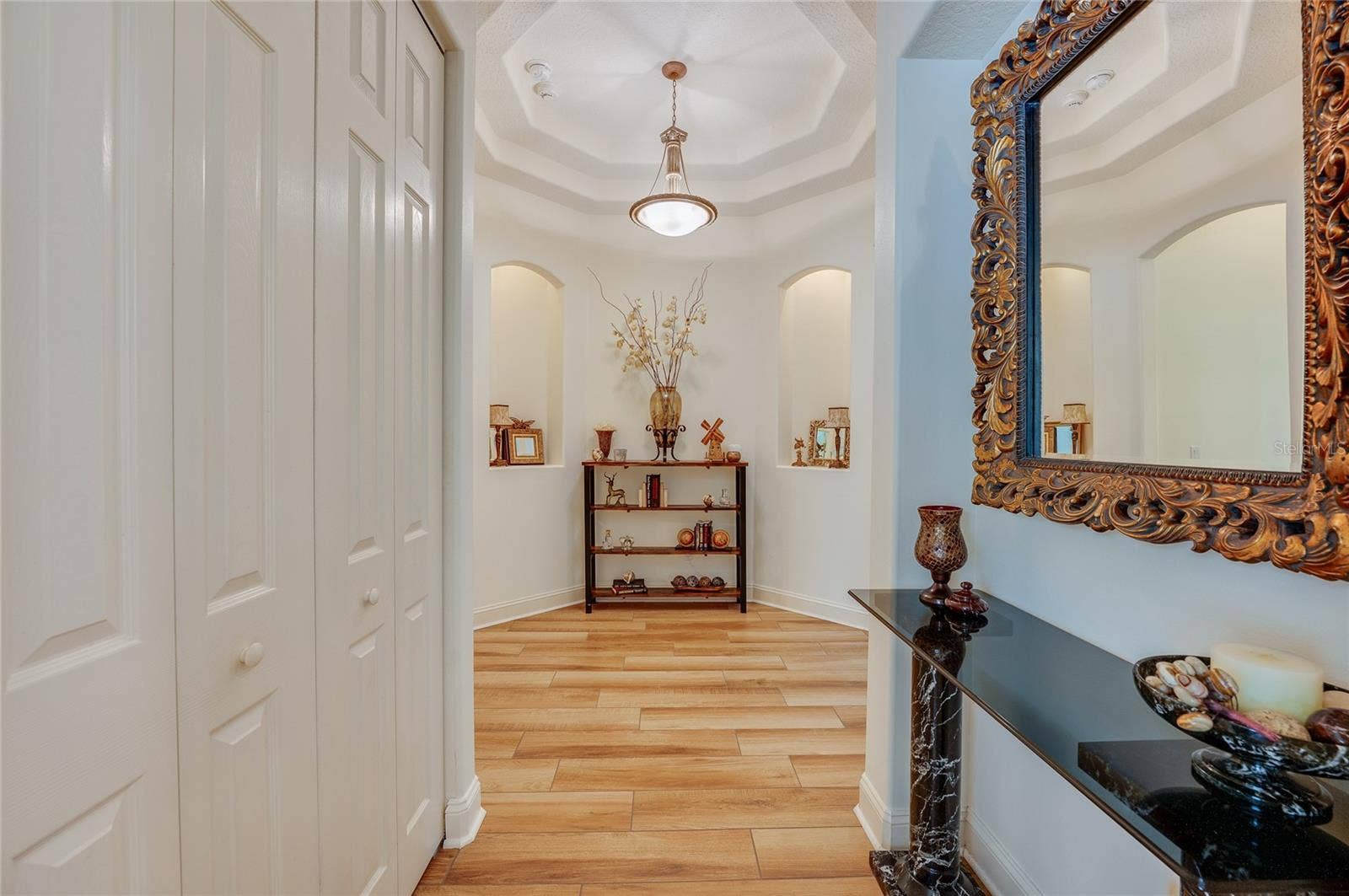 25 REMINGTON ROAD, Ormond Beach, FL 32174 Elegant hallway featuring warm tile flooring, recessed wall niches, and an octagonal tray ceiling with a hanging fixture.
