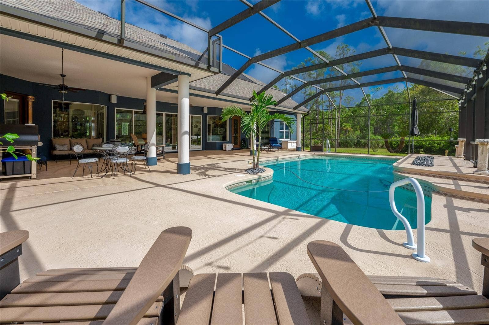 25 REMINGTON ROAD, Ormond Beach, FL 32174 Spacious pool deck highlighting textured flooring, a built-in pool feature, and ample shaded space under the attached porch cover.
