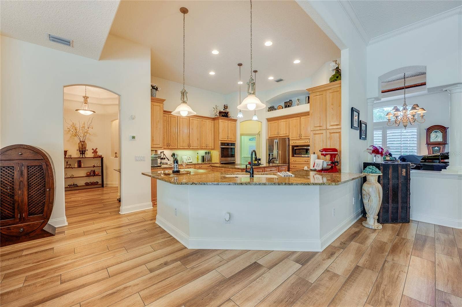 25 REMINGTON ROAD, Ormond Beach, FL 32174 Gourmet kitchen space showcasing continuous tile flooring, natural wood cabinetry, a raised breakfast bar, and pendant lighting.