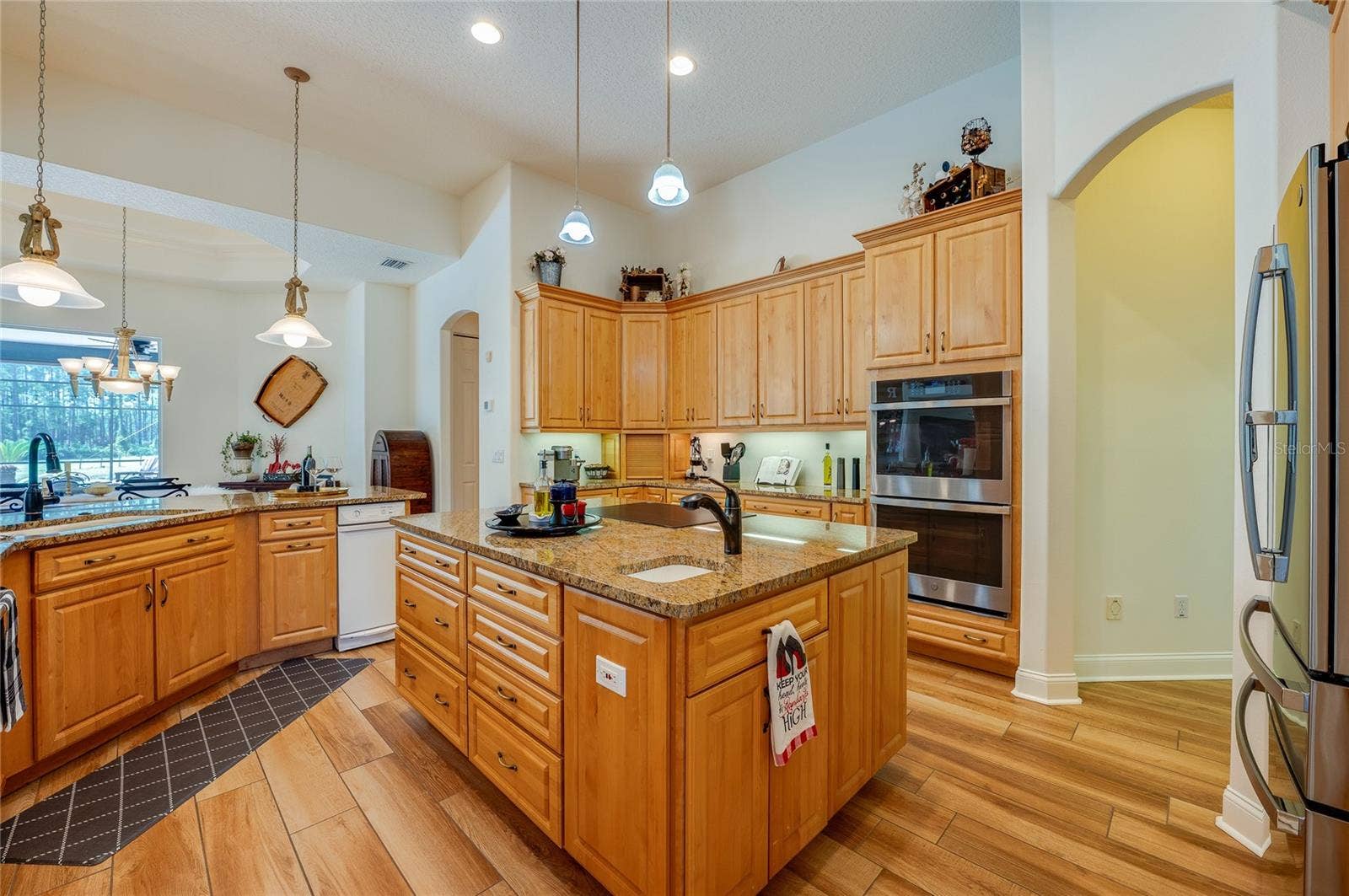 25 REMINGTON ROAD, Ormond Beach, FL 32174 Functional open kitchen layout complete with double wall ovens, rich wood cabinetry, a prep island with sink, and recessed lighting.