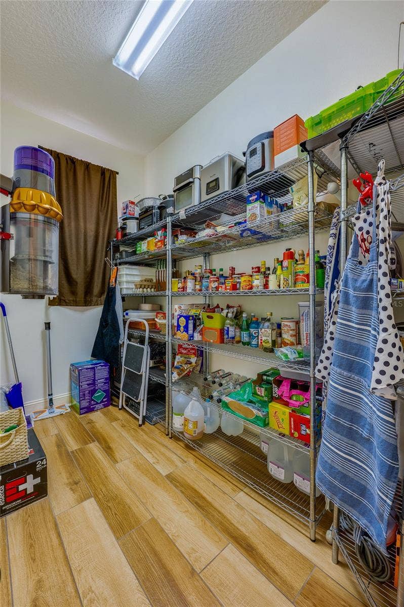 25 REMINGTON ROAD, Ormond Beach, FL 32174 Organized walk-in pantry featuring durable wire shelving units, warm tile flooring, and ample space for small appliances and provisions.
