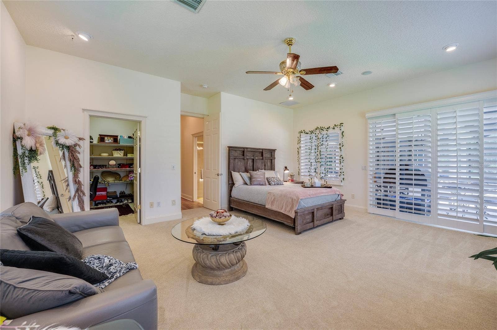 25 REMINGTON ROAD, Ormond Beach, FL 32174 Bedroom highlighted by plantation shutters and smooth sliding glass doors leading outside. A ceiling fan adds comfort to the brightly lit room.