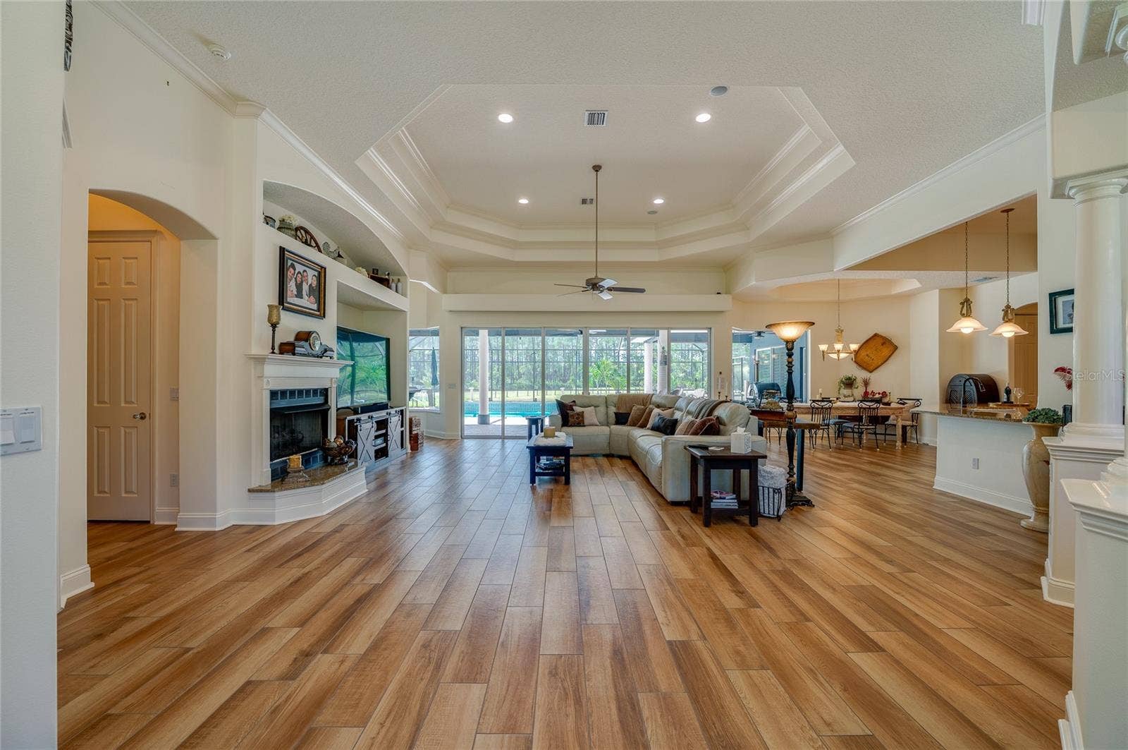 25 REMINGTON ROAD, Ormond Beach, FL 32174 Grand, wide-open living layout framed by a focal fireplace, detailed tray ceiling, and seamless flow into adjacent dining and kitchen zones.