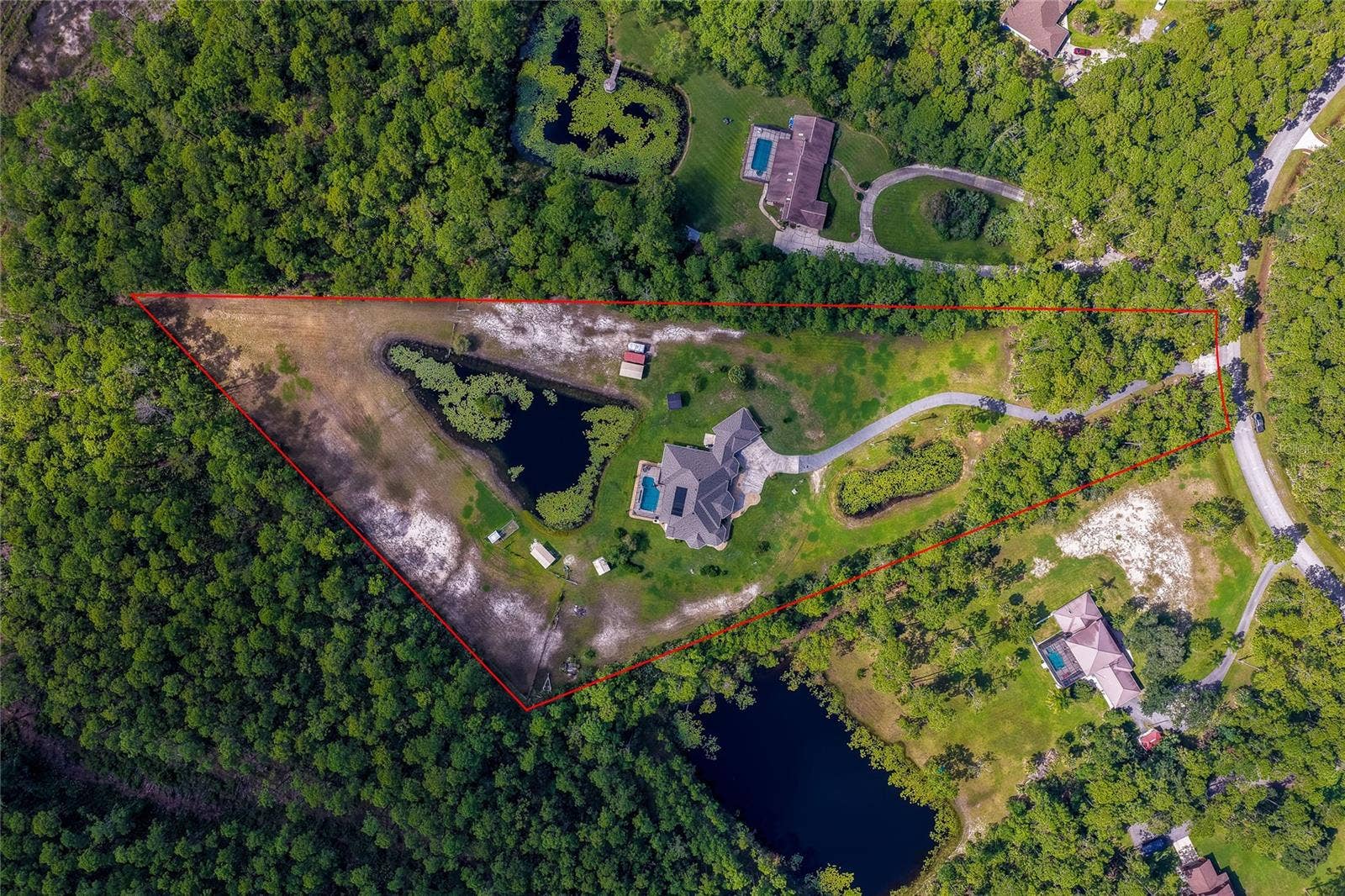 25 REMINGTON ROAD, Ormond Beach, FL 32174 Overhead property view outlining the extensive triangular lot boundaries encompassed by thick woodland, neighboring ponds, and surrounding acreage.