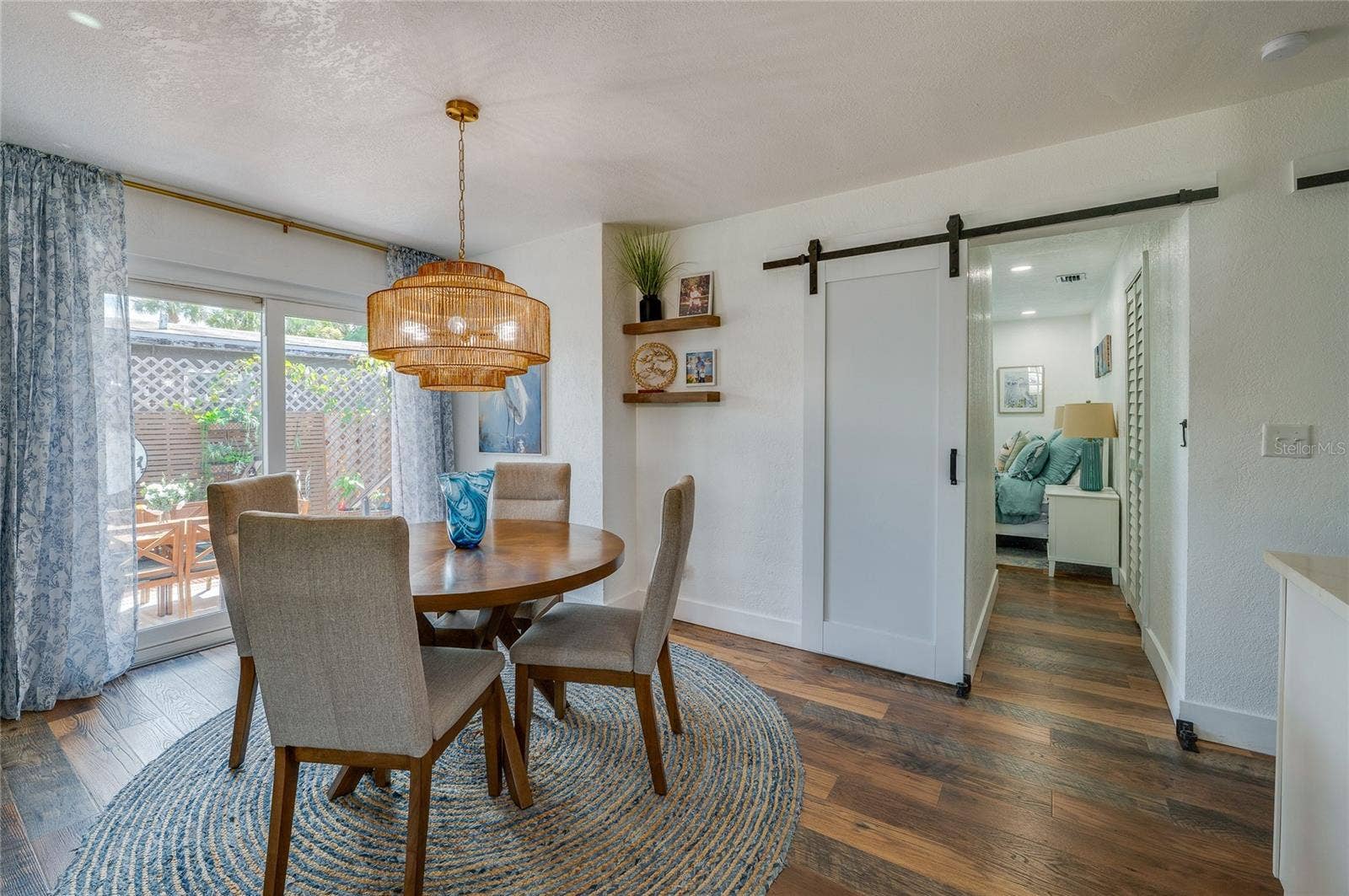 348 WOODLAND AVENUE, Daytona Beach, FL 32118 Dedicated dining nook highlighted by a woven pendant light fixture, sliding glass doors to the outside, and a modern white barn door leading down the hallway.