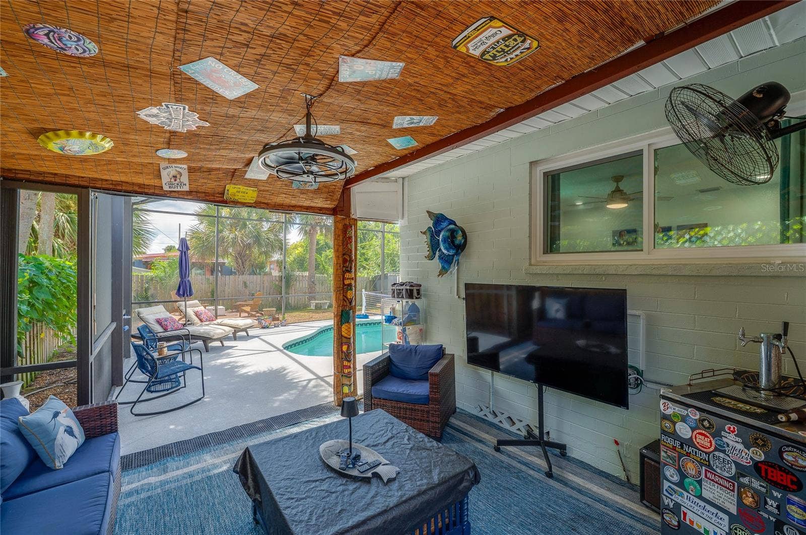 348 WOODLAND AVENUE, Daytona Beach, FL 32118 Covered screened porch featuring a woven bamboo ceiling and string lights. The space directly connects to the adjacent enclosed pool deck.