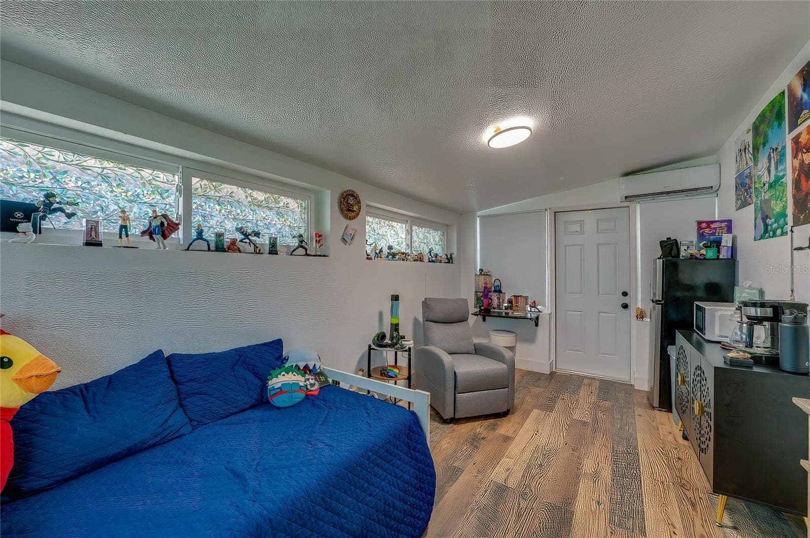348 WOODLAND AVENUE, Daytona Beach, FL 32118 Versatile bedroom or multipurpose living space highlighting rich LVP flooring, sloped ceilings, and long horizontal windows that offer plenty of natural light.