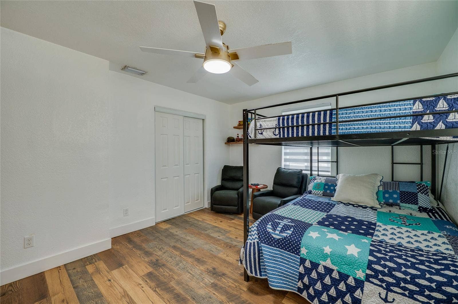 348 WOODLAND AVENUE, Daytona Beach, FL 32118 Bedroom view showcasing bright neutral walls, a ceiling fan, double sliding closet doors, and LVP flooring throughout.