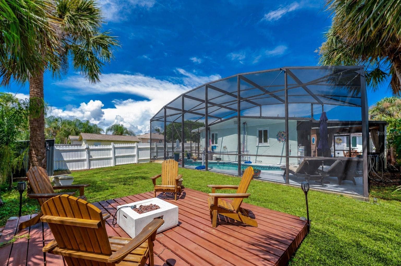 348 WOODLAND AVENUE, Daytona Beach, FL 32118 Raised wooden deck in the backyard with the screened pool enclosure and home exterior directly behind it.