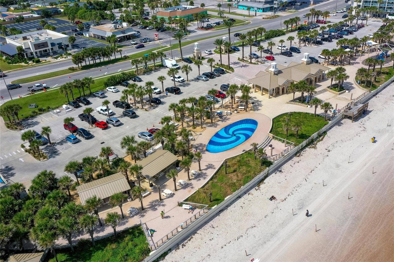 348 WOODLAND AVENUE, Daytona Beach, FL 32118 Sweeping aerial view captures Andy Romano Beachfront Park along the Atlantic coastline, featuring beachfront recreation areas, landscaped grounds, parking, and direct access to the sand.