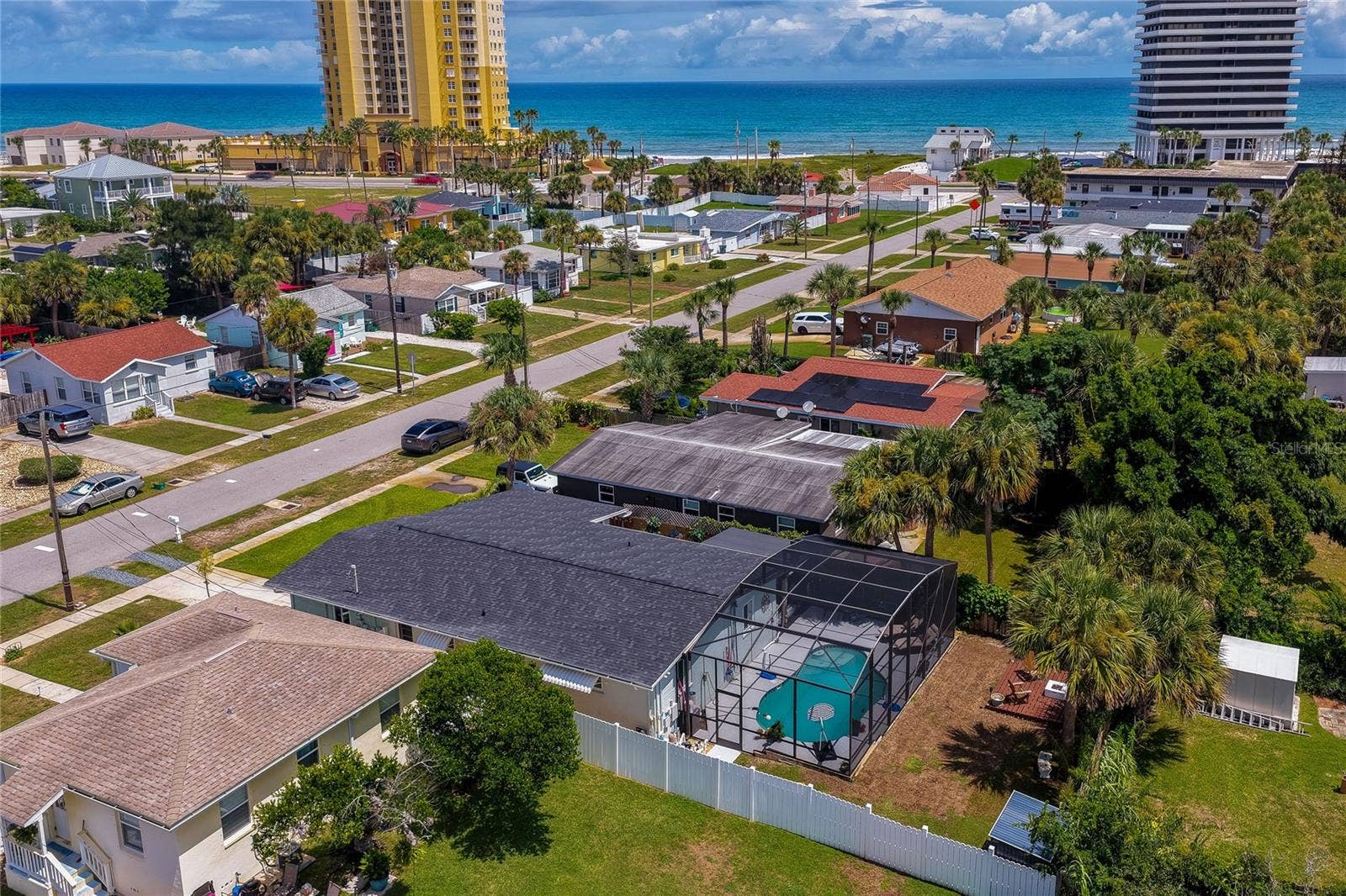 348 WOODLAND AVENUE, Daytona Beach, FL 32118 High-angle aerial photo displaying the homes layout, complete with its screened-in pool area, private yard, and proximity to the coastline.