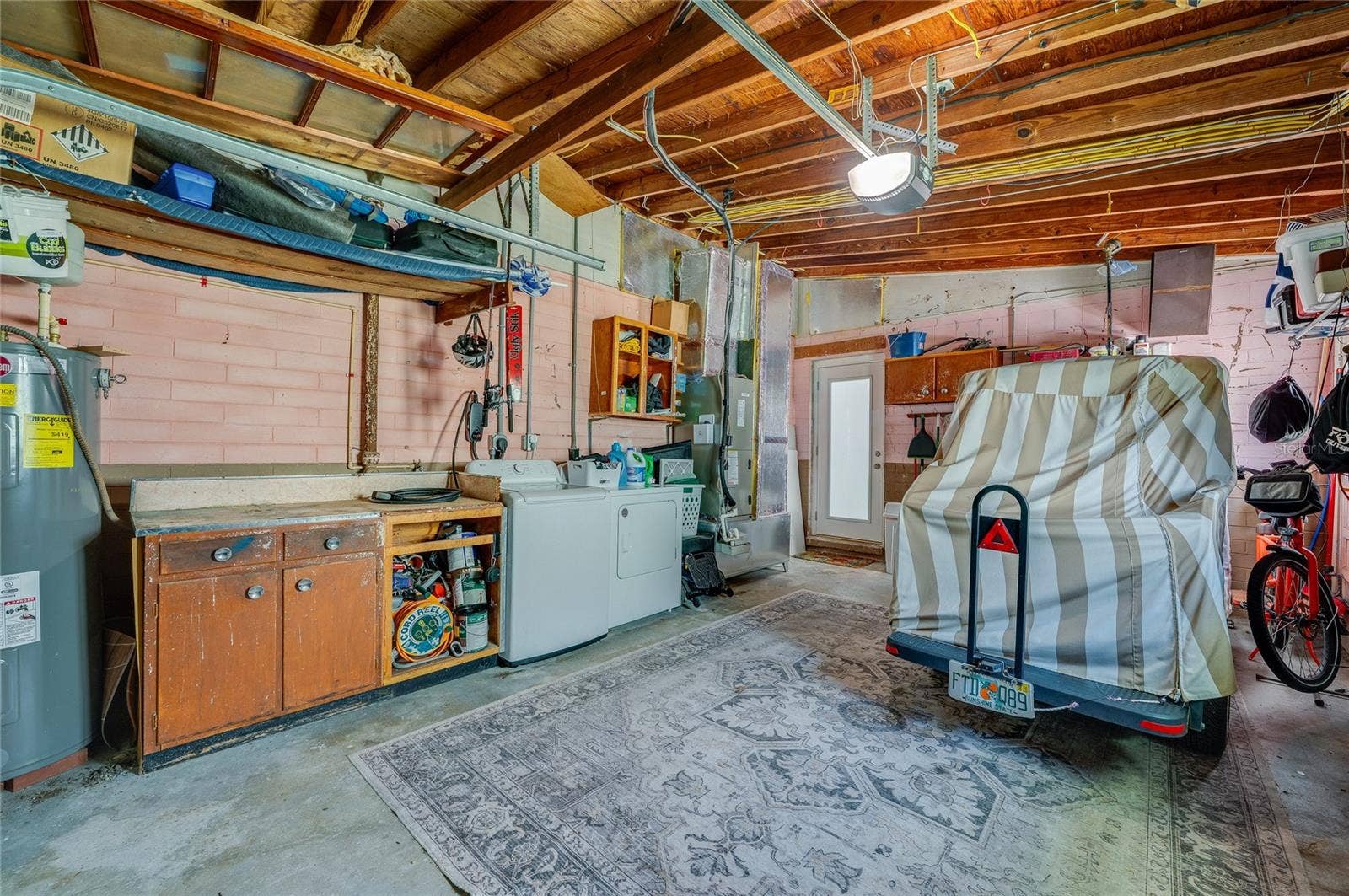348 WOODLAND AVENUE, Daytona Beach, FL 32118 Functional garage setup complete with in-unit laundry appliances, an integrated workbench, and dedicated space for vehicle storage.