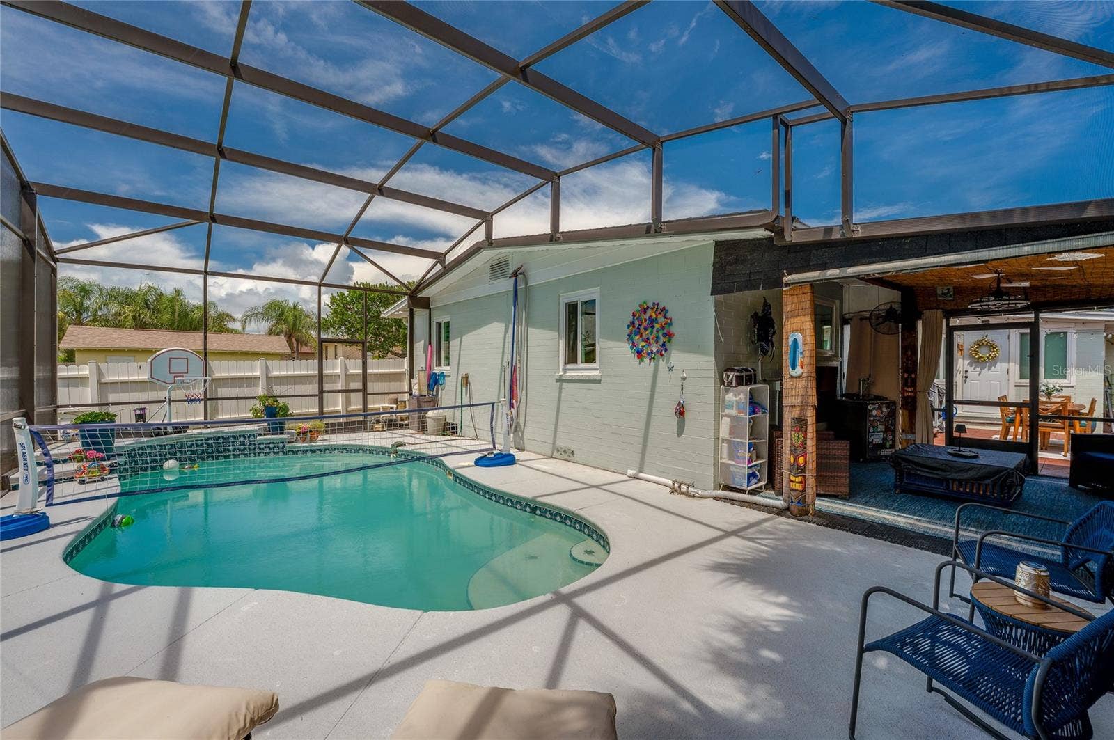 348 WOODLAND AVENUE, Daytona Beach, FL 32118 Spacious screened enclosure surrounding a custom in-ground pool with built-in steps. The layout seamlessly blends covered patio living with open-air sunbathing space.
