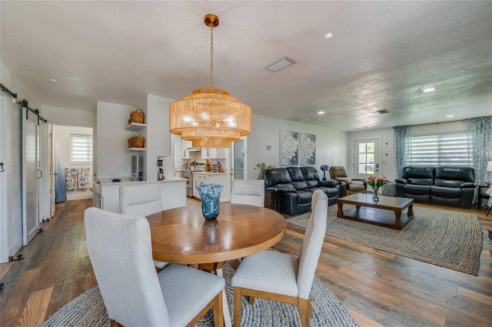348 WOODLAND AVENUE, Daytona Beach, FL 32118 Expansive view of the open-plan main level showing the fluid transition from the dining space through to the main living area and kitchen entry.
