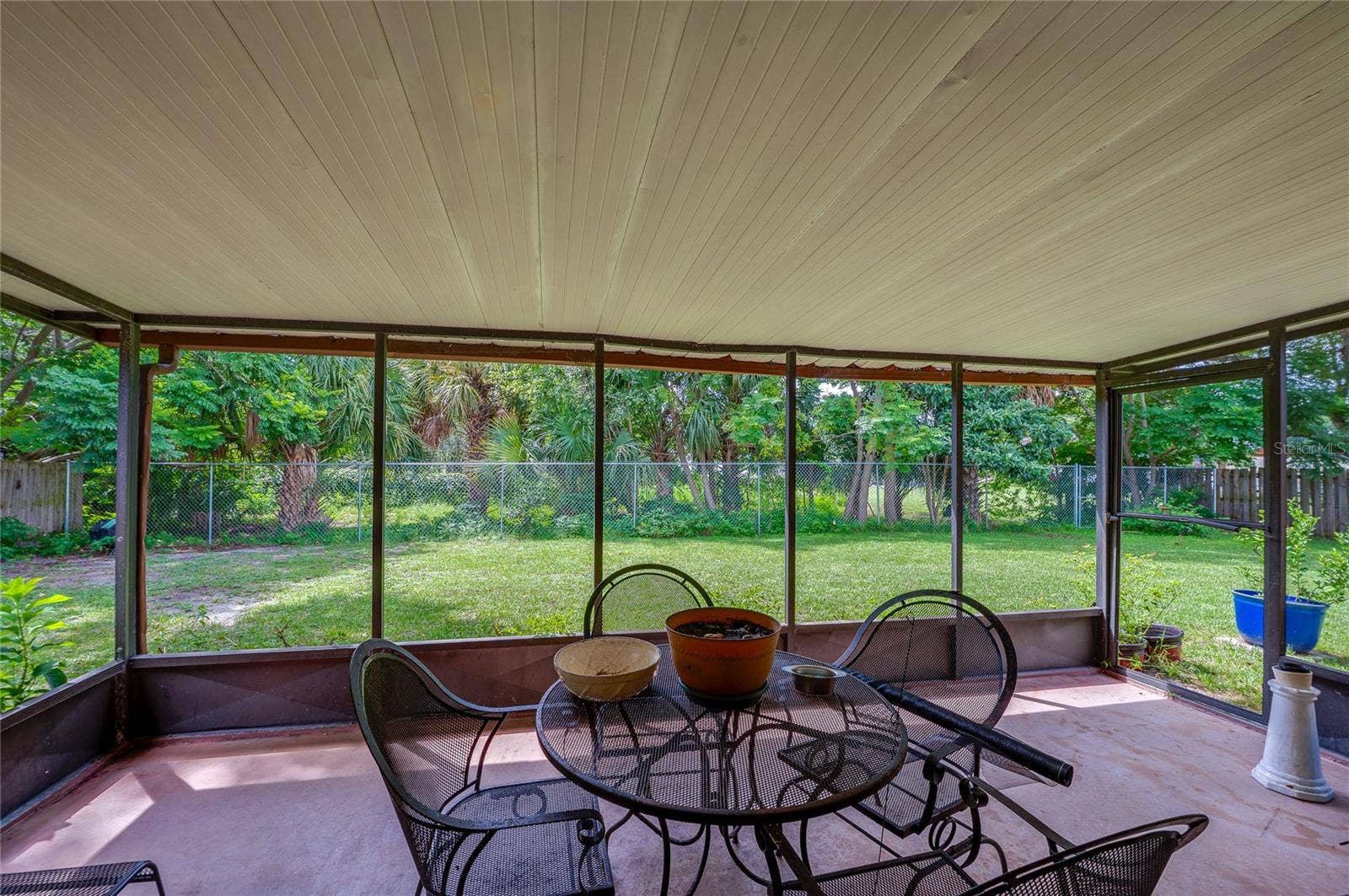 146 WESTWOOD DRIVE, Daytona Beach, FL 32119 Screened-in back porch providing full views of the green backyard and surrounding tree line.