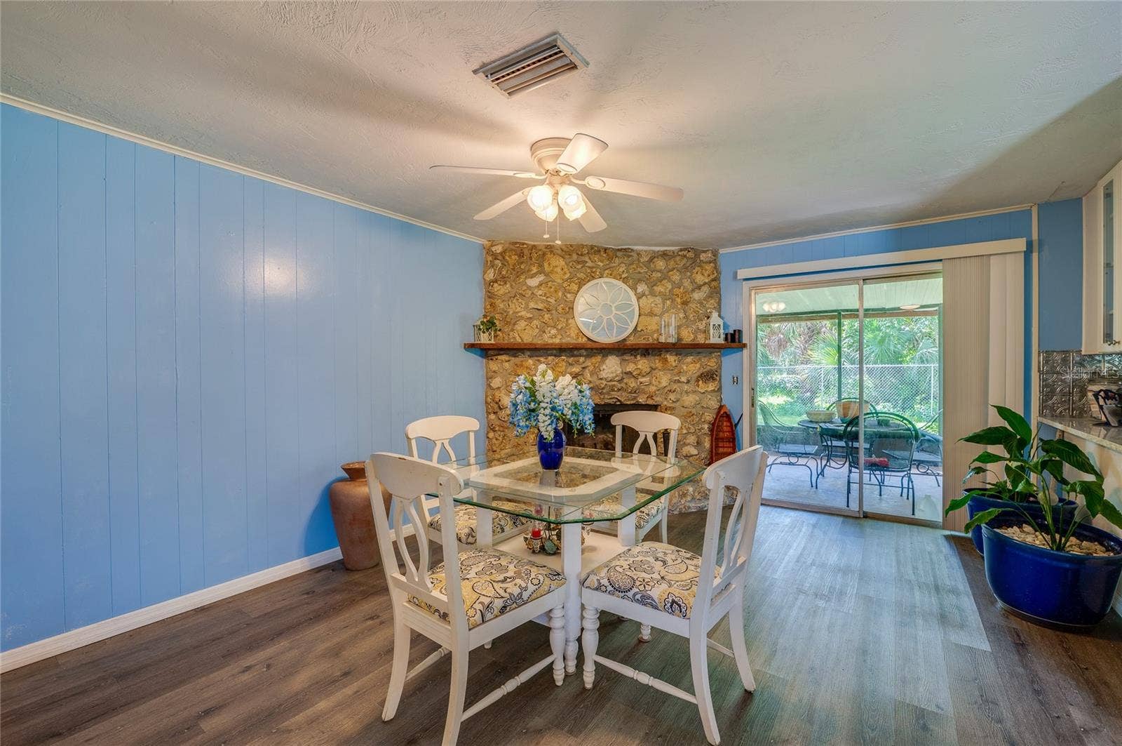 146 WESTWOOD DRIVE, Daytona Beach, FL 32119 Inviting space highlighted by a floor-to-ceiling stone fireplace, light blue paneling, LVP flooring, and direct sliding glass door access to the back patio.