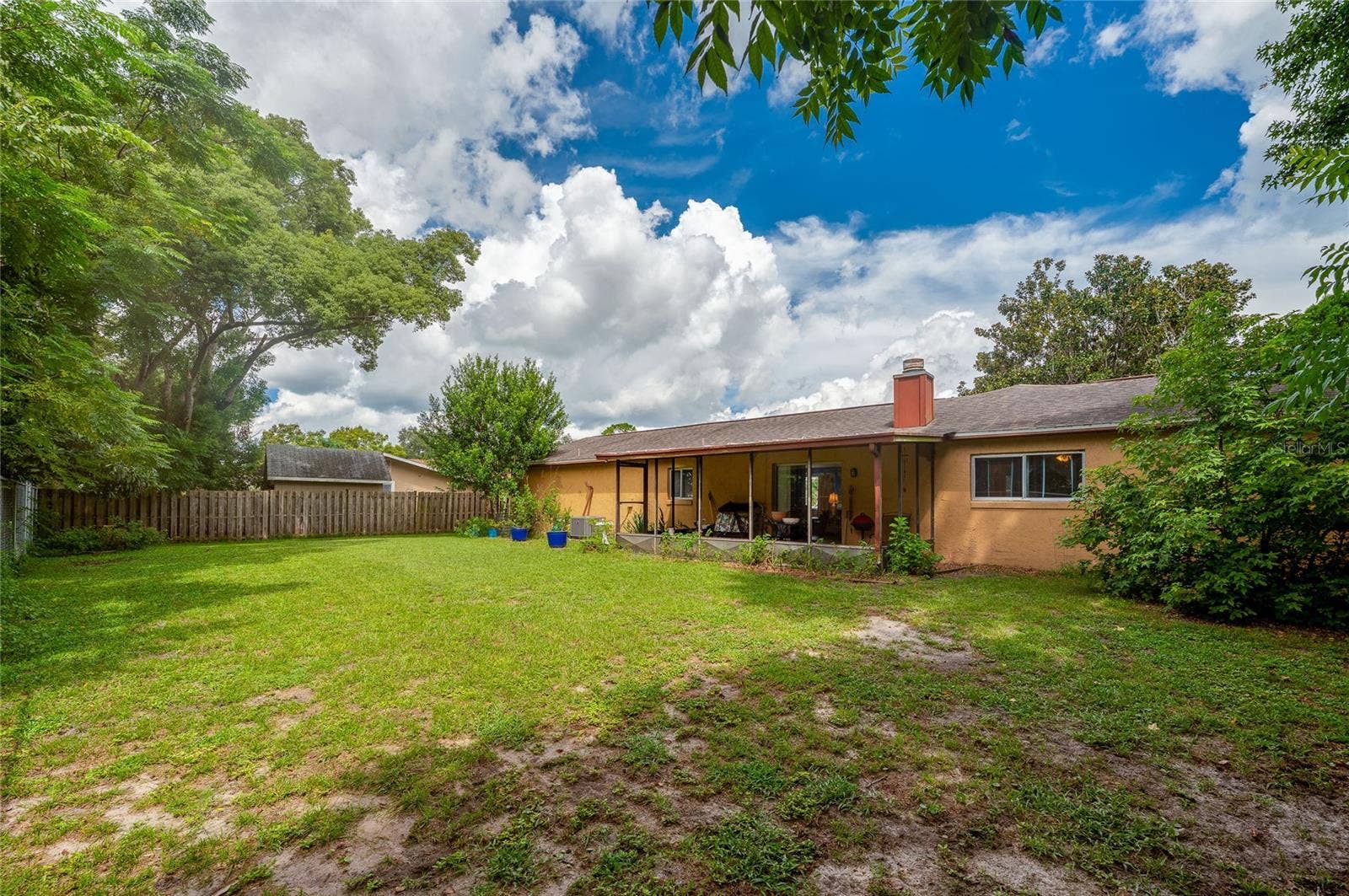 146 WESTWOOD DRIVE, Daytona Beach, FL 32119 Large grassy backyard framed by mature shade trees and a fully enclosed fence along the rear of the property.