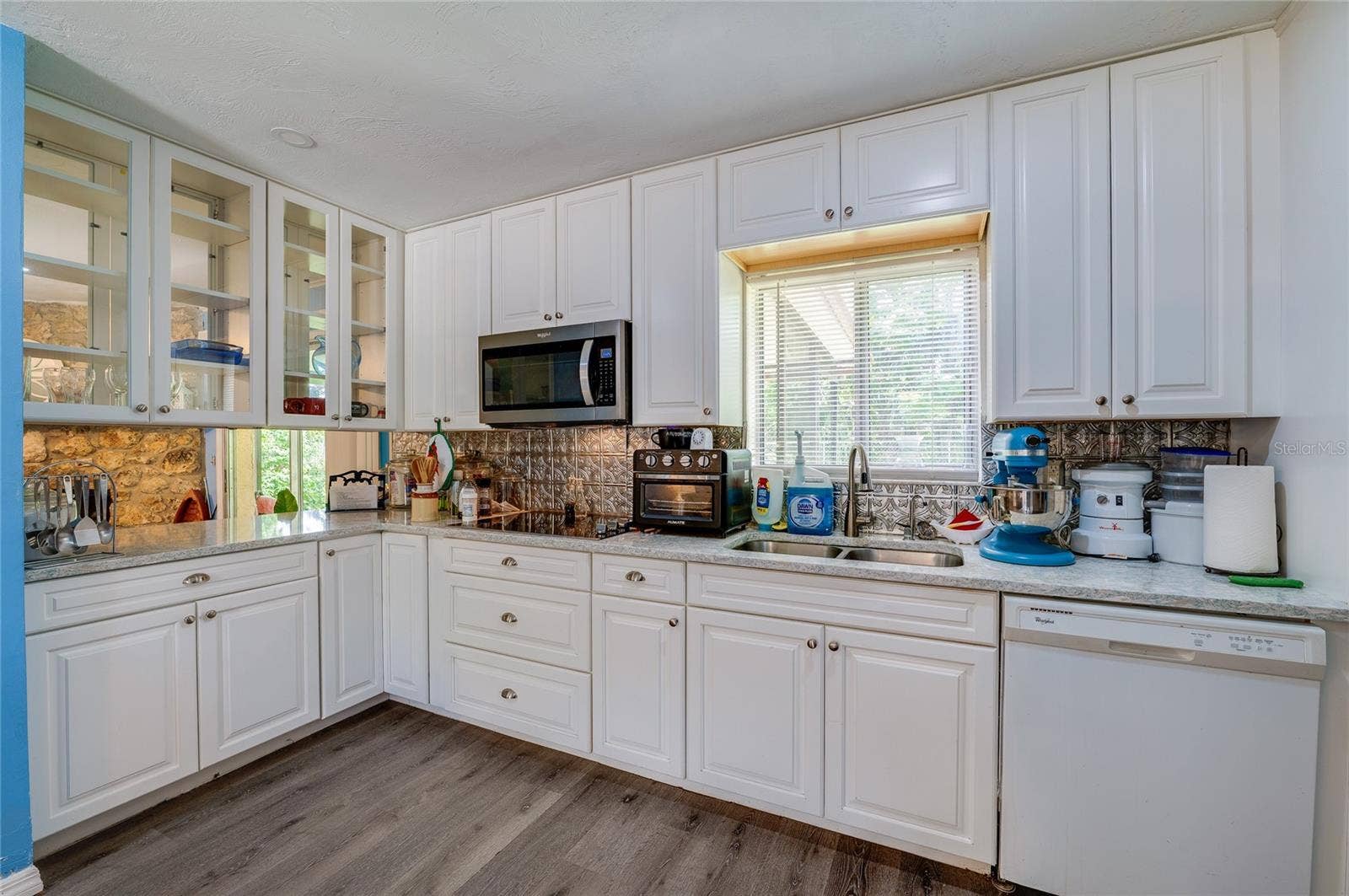146 WESTWOOD DRIVE, Daytona Beach, FL 32119 Functional kitchen layout complete with white cabinetry, glass-front upper cupboards, a double sink under a bright window, and built-in appliances.