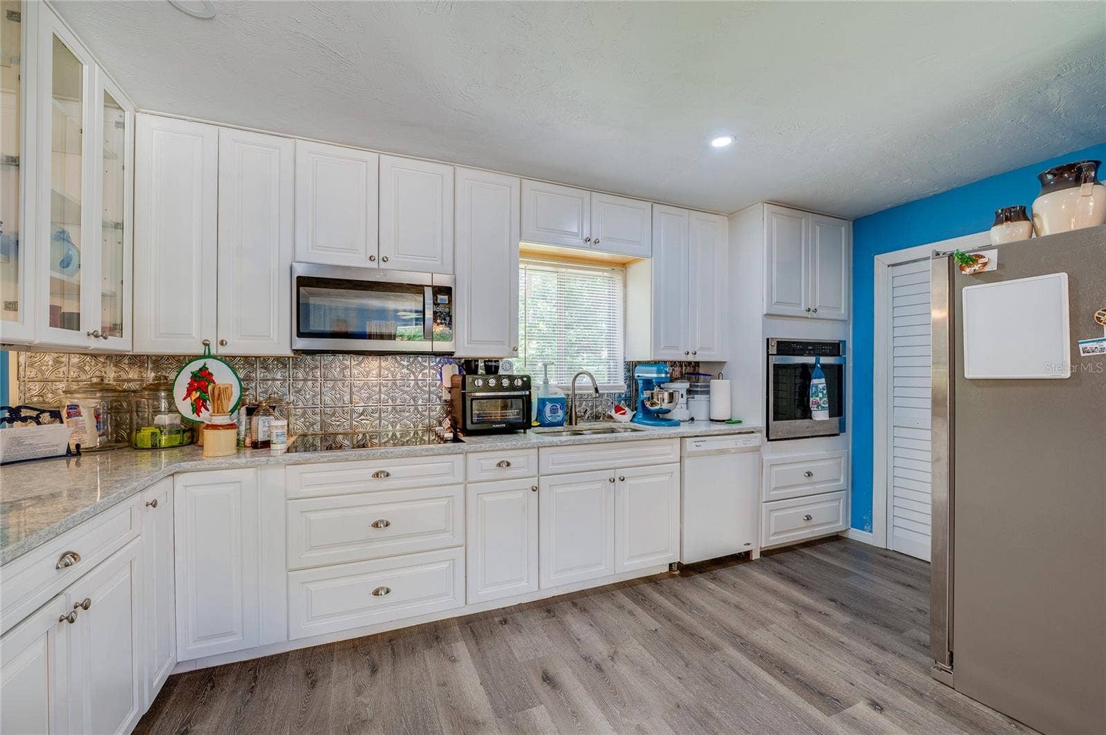 146 WESTWOOD DRIVE, Daytona Beach, FL 32119 Well-equipped kitchen featuring crisp white cabinetry, textured tile backsplash, built-in appliances, and light grey LVP flooring.