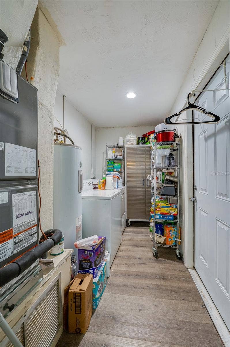 146 WESTWOOD DRIVE, Daytona Beach, FL 32119 Utility and laundry corridor featuring LVP flooring, white cabinetry storage, and dedicated space for a washer and dryer.